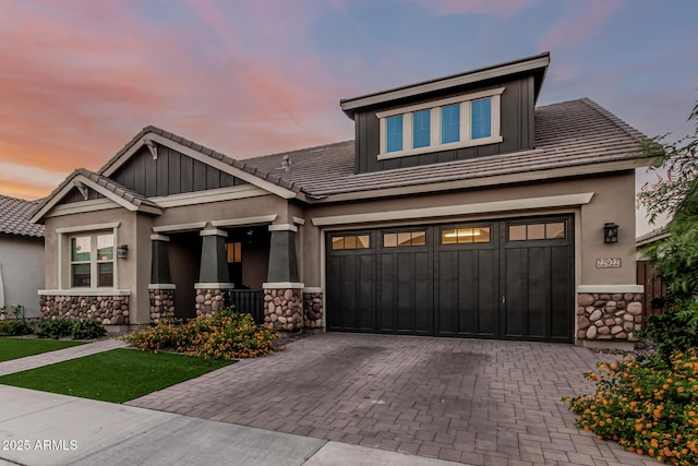 craftsman inspired home featuring stone siding, decorative driveway, stucco siding, and a tiled roof