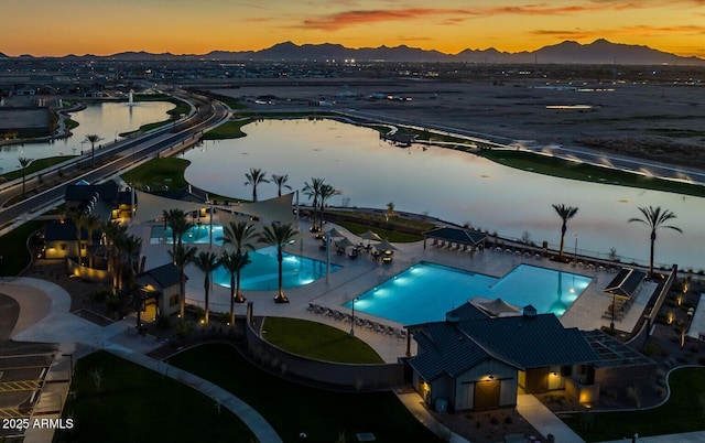 aerial view at dusk of view of pool and a water and mountain view