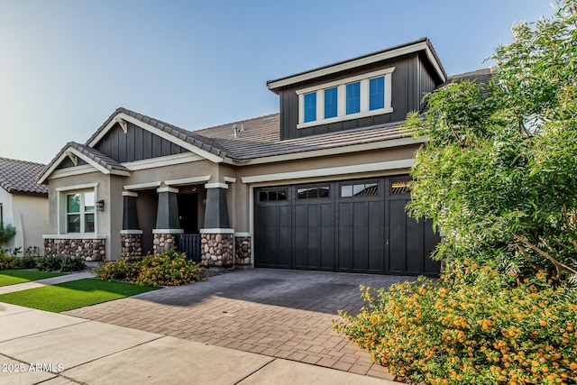 craftsman-style house with decorative driveway, stone siding, board and batten siding, and an attached garage