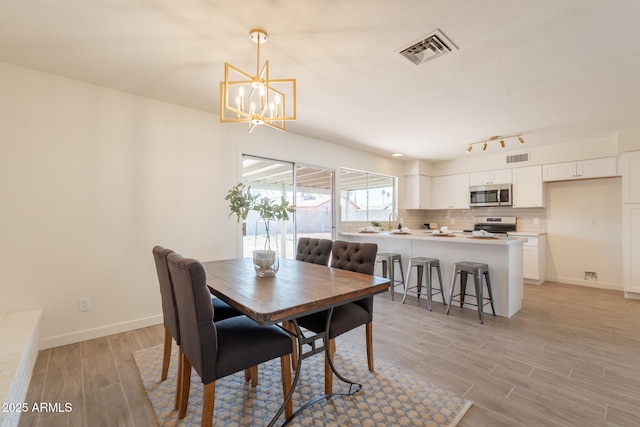 3118 S Los Altos Dr, Mesa, AZ 85202 - dining area featuring a chandelier, light wood-type flooring, baseboards, and rail lighting