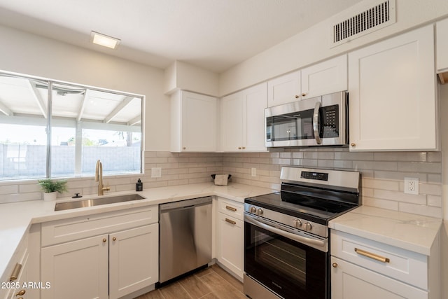 3118 S Los Altos Dr, Mesa, AZ 85202 - kitchen featuring appliances with stainless steel finishes, a sink, decorative backsplash, white cabinets, and light wood-style floors