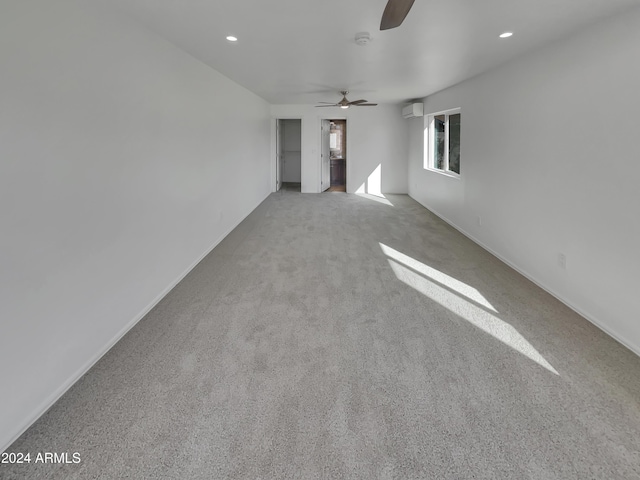 unfurnished living room with a wall mounted air conditioner, light colored carpet, and ceiling fan