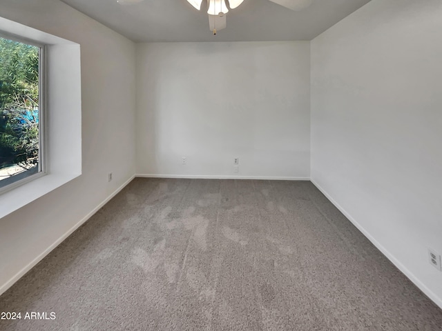 carpeted spare room featuring ceiling fan and a healthy amount of sunlight