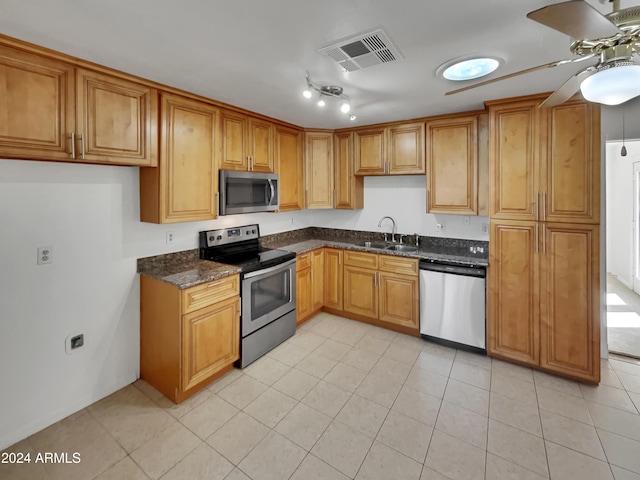 kitchen featuring ceiling fan, sink, stainless steel appliances, dark stone countertops, and light tile patterned floors