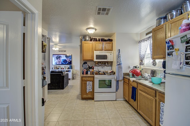 kitchen with light tile patterned floors, white appliances, a textured ceiling, and ceiling fan