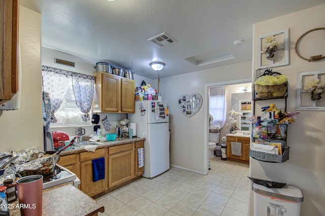 kitchen featuring white fridge, light tile patterned floors, and a textured ceiling