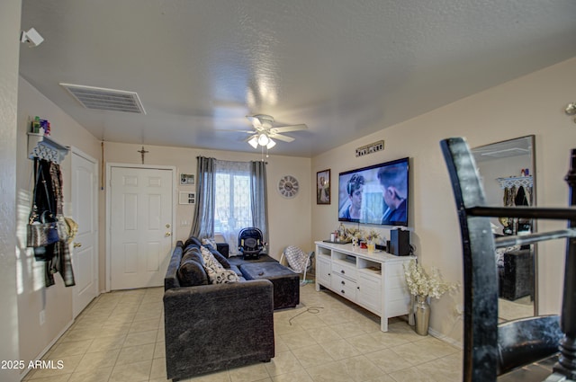 living room with ceiling fan, a textured ceiling, and light tile patterned flooring