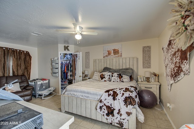 tiled bedroom featuring a textured ceiling, a walk in closet, a closet, and ceiling fan