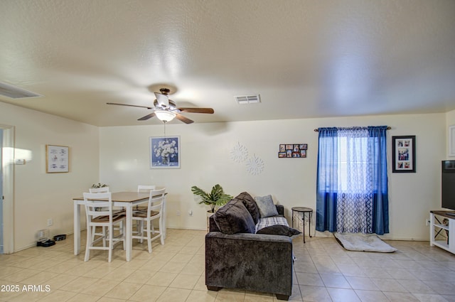 living room featuring a textured ceiling, ceiling fan, and light tile patterned flooring