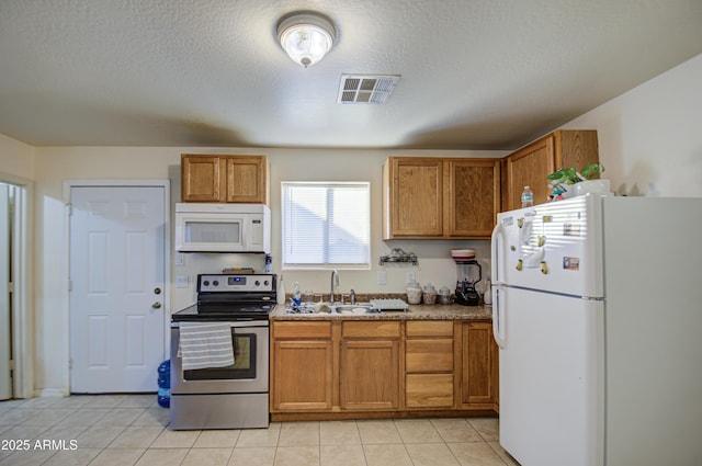 kitchen featuring white appliances, sink, a textured ceiling, and light tile patterned floors