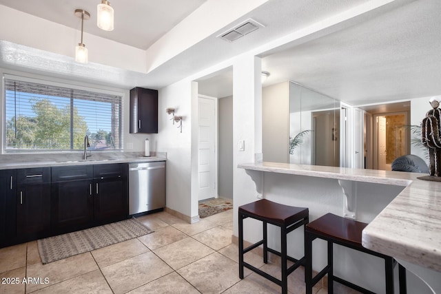 kitchen featuring sink, light tile patterned floors, stainless steel dishwasher, a kitchen breakfast bar, and pendant lighting