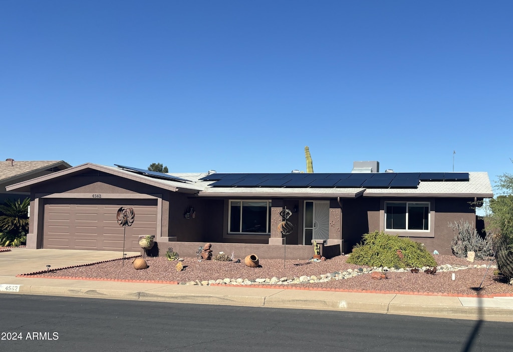 single story home with solar panels and a garage