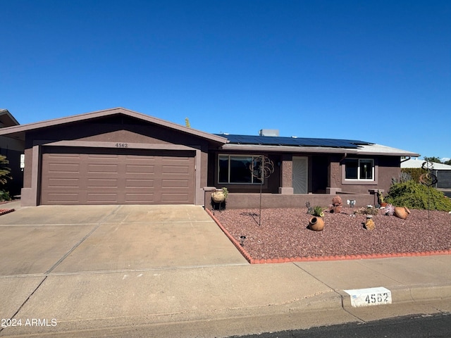 ranch-style house with a garage and solar panels