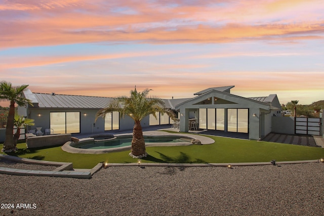 back house at dusk with a patio area and a swimming pool with hot tub