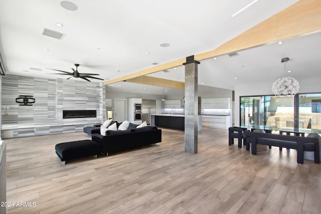 living room with light hardwood / wood-style floors, sink, ceiling fan with notable chandelier, and vaulted ceiling