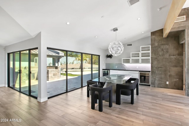 dining area featuring light hardwood / wood-style flooring, wine cooler, a chandelier, and vaulted ceiling