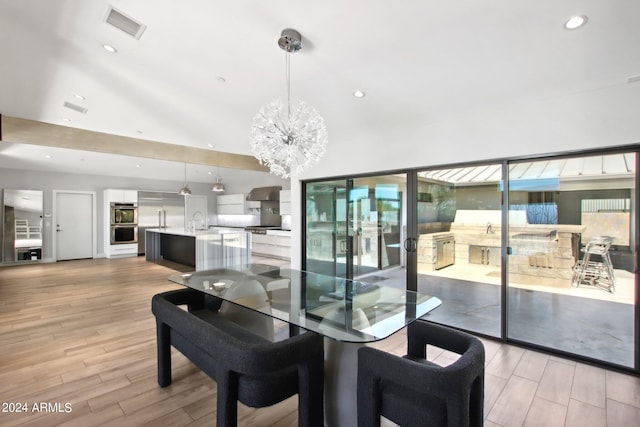 dining area featuring light hardwood / wood-style floors, lofted ceiling, sink, and a chandelier