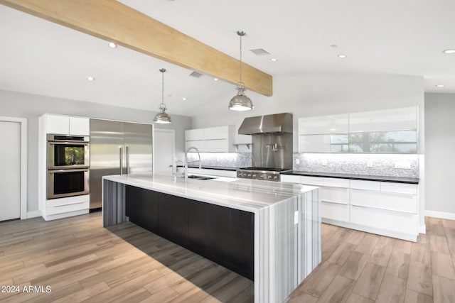 kitchen featuring a large island, white cabinets, lofted ceiling with beams, appliances with stainless steel finishes, and light hardwood / wood-style floors