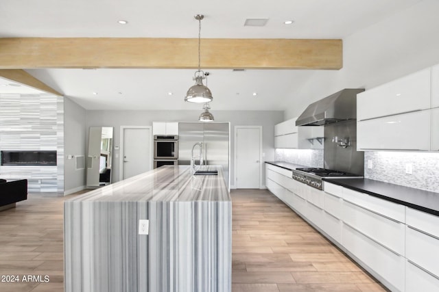 kitchen featuring appliances with stainless steel finishes, white cabinets, pendant lighting, and light hardwood / wood-style floors