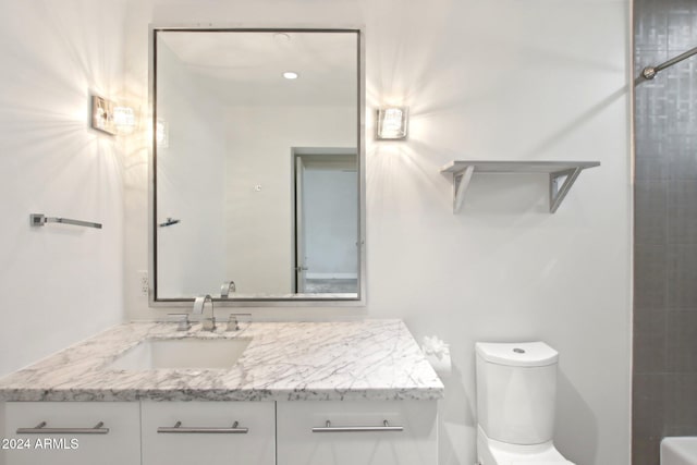 bathroom featuring vanity, tiled shower, and toilet