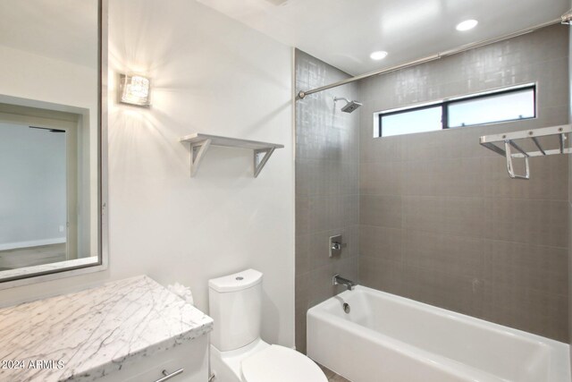 full bathroom featuring toilet, tiled shower / bath, and vanity