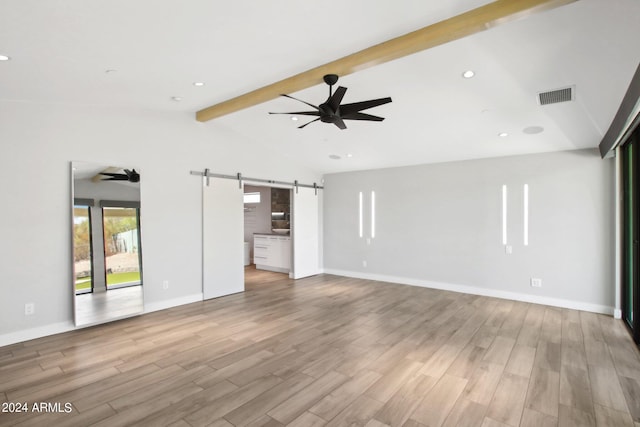 unfurnished living room featuring ceiling fan, lofted ceiling with beams, light hardwood / wood-style floors, and a barn door