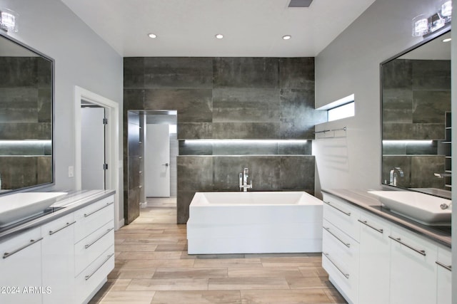 bathroom featuring vanity, wood-type flooring, and a bath