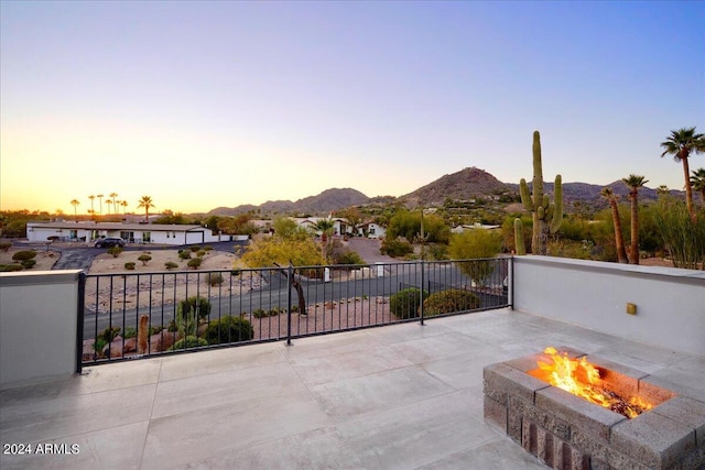 patio terrace at dusk featuring an outdoor fire pit and a mountain view