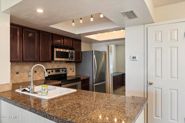 4015 N 78th St Unit 135, Scottsdale, AZ 85251 - kitchen with appliances with stainless steel finishes, a tray ceiling, tasteful backsplash, dark brown cabinets, and a peninsula