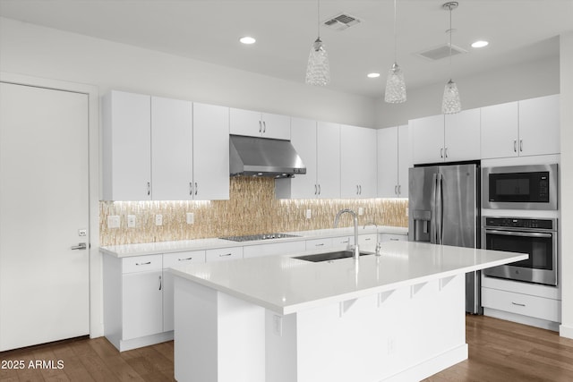 kitchen featuring sink, decorative light fixtures, appliances with stainless steel finishes, a kitchen island with sink, and white cabinets