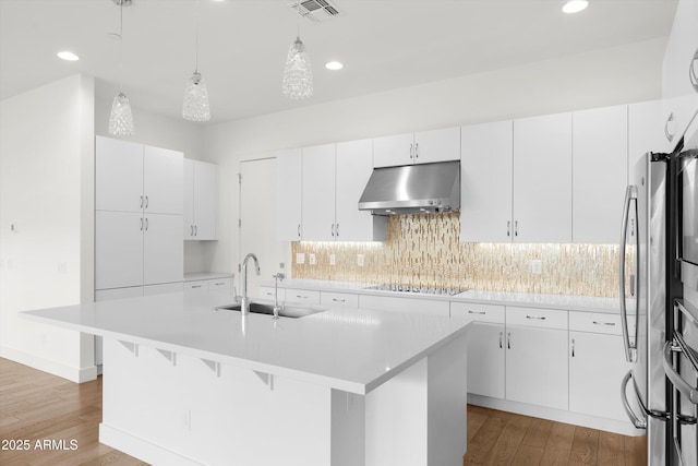 kitchen with sink, white cabinetry, range hood, a center island with sink, and black electric cooktop