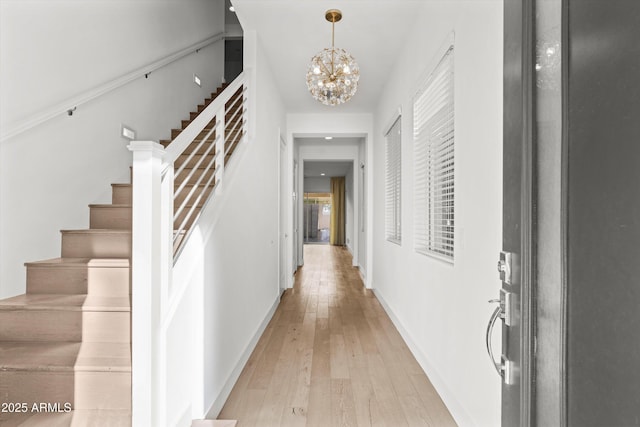 hall with an inviting chandelier and light hardwood / wood-style flooring