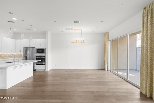 kitchen with sink, a breakfast bar area, decorative light fixtures, appliances with stainless steel finishes, and light hardwood / wood-style floors