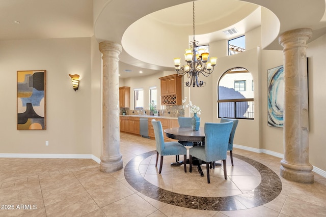 dining area with ornate columns, a towering ceiling, and an inviting chandelier