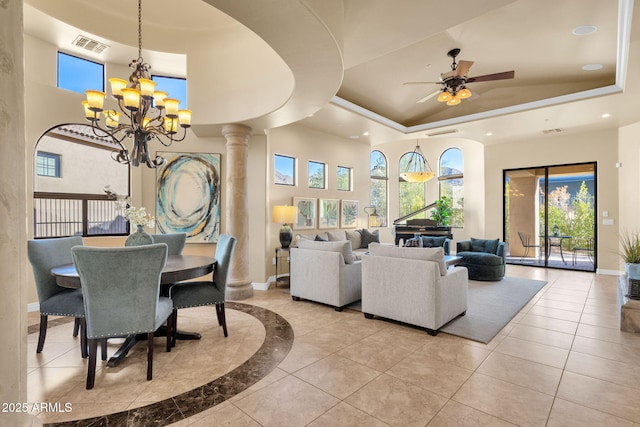 dining area with a towering ceiling, a raised ceiling, and decorative columns