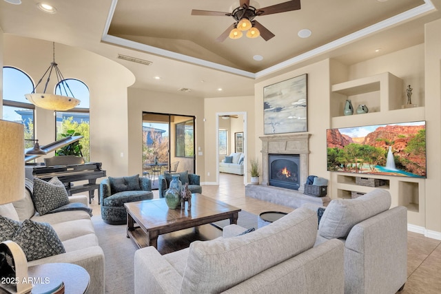 tiled living room featuring vaulted ceiling, ceiling fan, and a tray ceiling