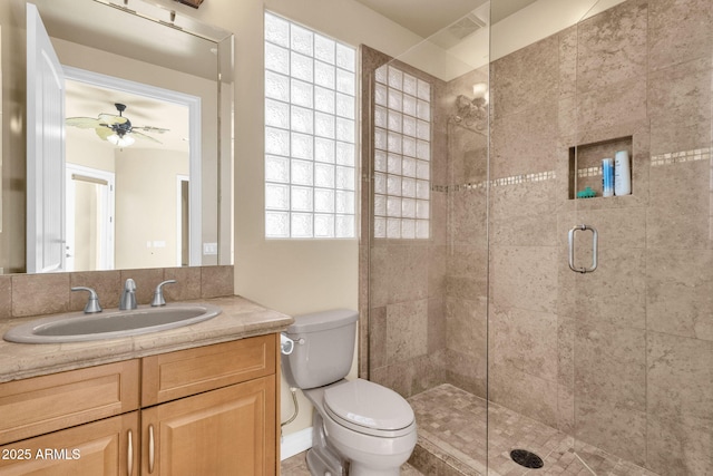 bathroom featuring ceiling fan, vanity, toilet, and a shower with shower door