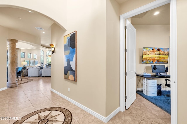 hall featuring decorative columns and light tile patterned floors