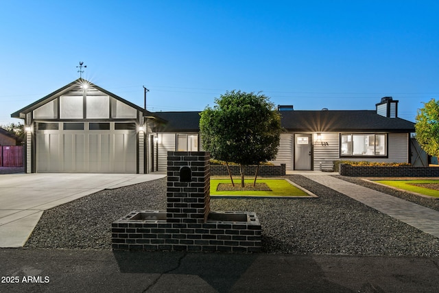 view of front of home with a chimney, concrete driveway, and an attached garage
