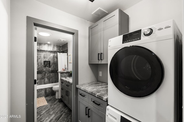 laundry area with cabinet space, dark wood-style flooring, and visible vents