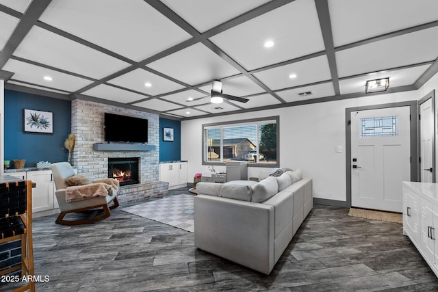living area featuring recessed lighting, a brick fireplace, dark wood-type flooring, coffered ceiling, and plenty of natural light
