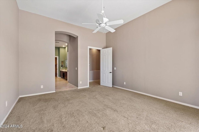 unfurnished bedroom featuring light colored carpet, connected bathroom, and ceiling fan