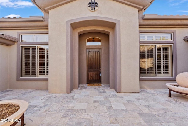 view of exterior entry with a patio area