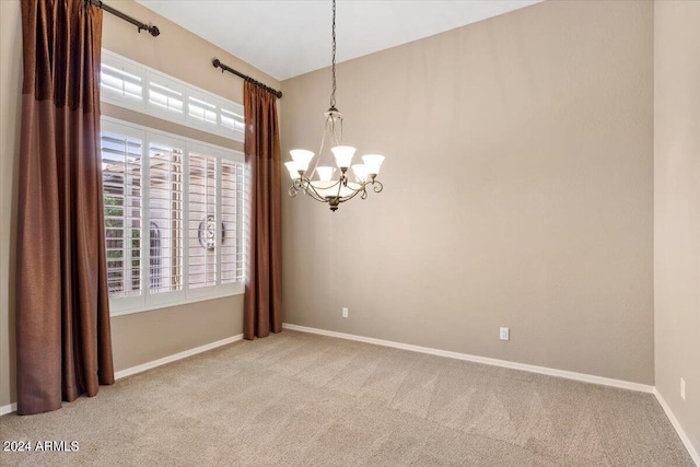 empty room featuring light carpet and an inviting chandelier