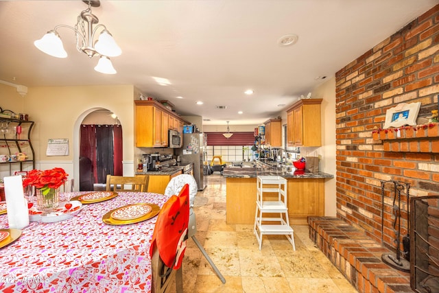 kitchen featuring a kitchen breakfast bar, pendant lighting, appliances with stainless steel finishes, and a chandelier