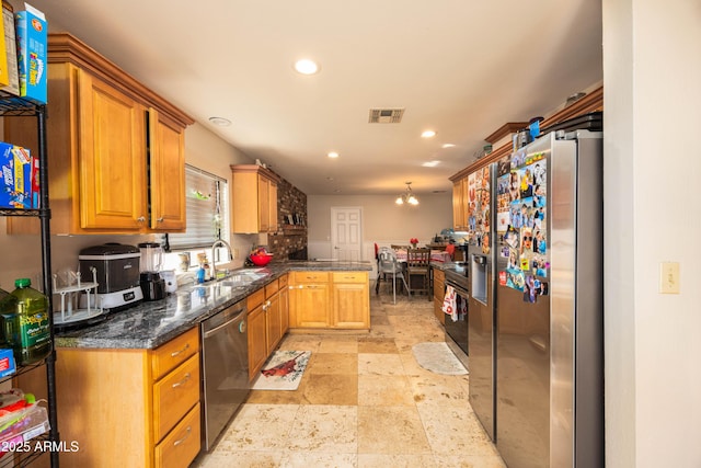 kitchen featuring appliances with stainless steel finishes, dark stone countertops, kitchen peninsula, and sink