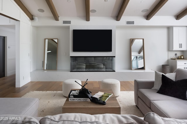 living room with beamed ceiling, a fireplace, and light hardwood / wood-style flooring