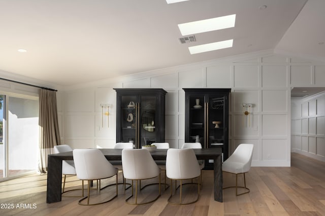 dining area featuring crown molding, vaulted ceiling, and light wood-type flooring