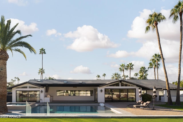 back of house with a swimming pool with hot tub and a patio