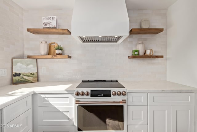 kitchen with high end white range, white cabinetry, light stone counters, decorative backsplash, and custom exhaust hood